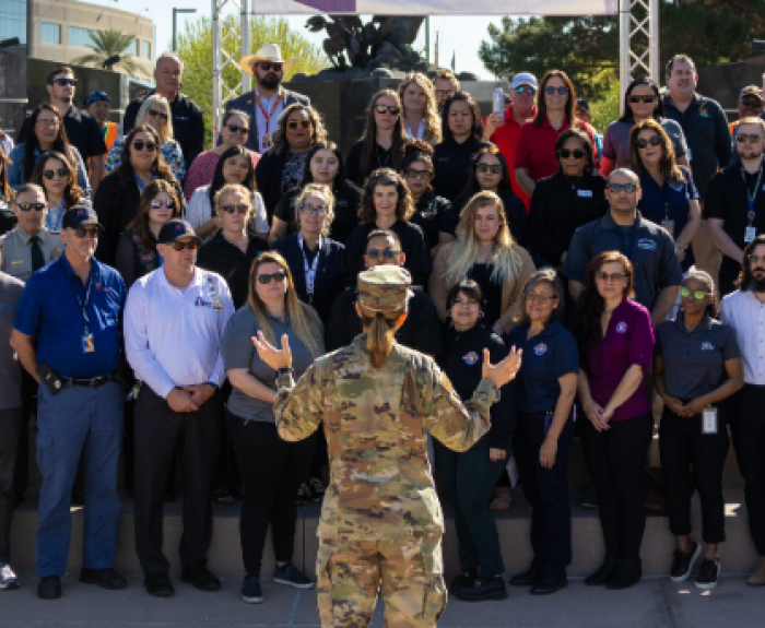 Person in fatigues talks to a crowd of agency recruiters