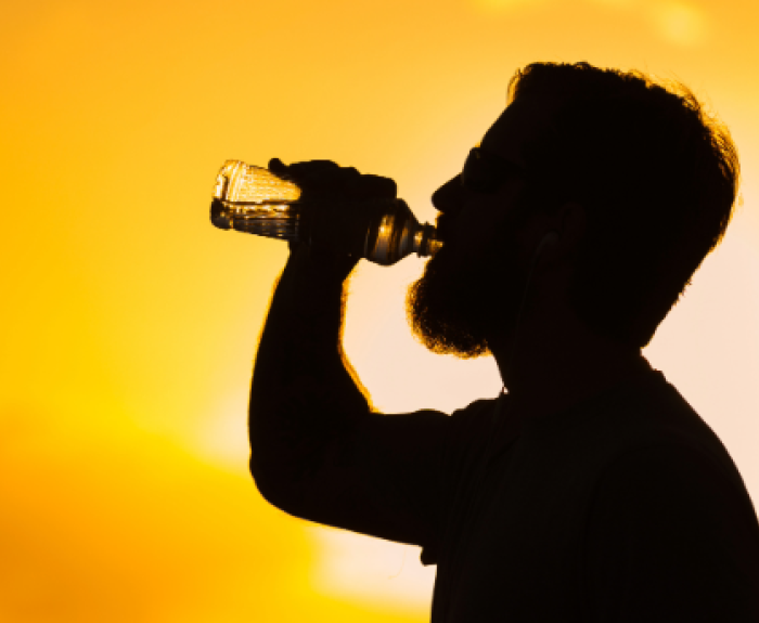 ADOA News Release label and a silhouette of a man drinking water with an intense sun behind him
